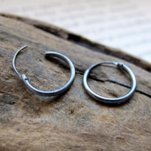 May include: A pair of silver hoop earrings. The earrings are simple and understated, with a smooth, polished finish.