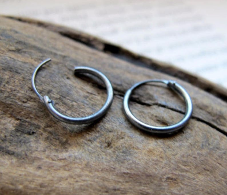 May include: A pair of silver hoop earrings. The earrings are simple and understated, with a smooth, polished finish.