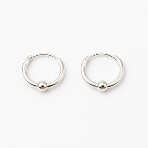 Two silver hoop earrings with a small silver ball at the bottom of each hoop.