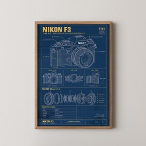 May include: A blue technical blueprint poster of a Nikon F3 35mm SLR camera. The print features white line drawings of the camera body from multiple angles, a disassembled Nikkor 50mm f/1.4 lens, and technical specifications in yellow text.