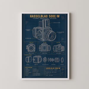 Puede incluir: Un póster de plano técnico de una cámara Hasselblad 500C/M sobre un fondo azul oscuro. La impresión presenta dibujos lineales blancos de la cámara, una vista de despiece y especificaciones detalladas que incluyen dimensiones en centímetros.