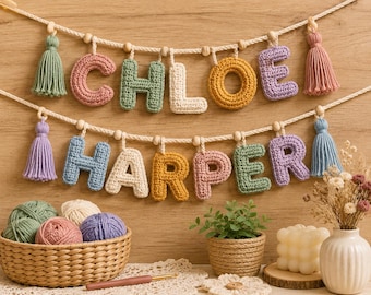 Puede incluir: Dos filas de guirnaldas de letras de ganchillo que forman los nombres CHLOE y HARPER. Las letras son de varios colores pastel, suspendidas en una cuerda blanca con cuentas de madera y borlas en los extremos. Textura de punto visible.