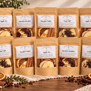 May include: Ten brown paper pouches labeled Lillard Mercantile containing dried fruit, cinnamon sticks, star anise, and cloves. The labels feature scent names like Apple Pie, Sweater Weather, Pumpkin Patch, and Cozy Cafe with ingredient lists.