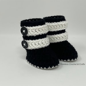 May include: Black and white crocheted baby booties with black buttons. Timeless Crochet & Crafts.