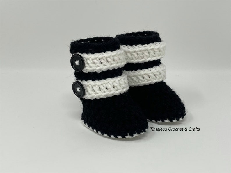 May include: Black and white crocheted baby booties with black buttons. Timeless Crochet & Crafts.