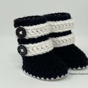 May include: Black and white crocheted baby booties with black buttons. The booties have a white crocheted trim around the top and bottom.