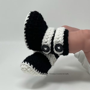 May include: Black and white crocheted baby booties with white trim and black buttons. The booties have a heart-shaped design on the buttons. Timeless Crochet & Crafts.