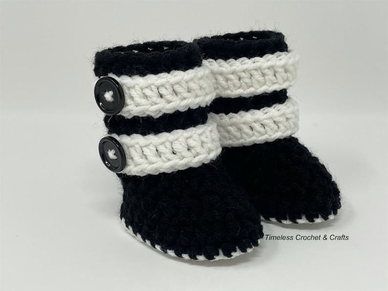 May include: Black and white crocheted baby booties with black buttons. Timeless Crochet & Crafts.