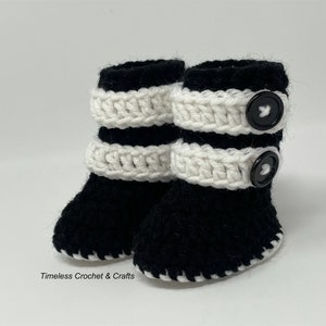 May include: A pair of black and white crocheted baby booties with black buttons. The booties have a white crocheted band around the top and a black crocheted sole.