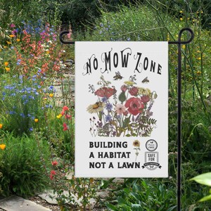 K&ouml;nnte beinhalten: Eine wei&szlig;e Gartenflagge mit dem Text "NO MOW ZONE" und einer floralen Illustration. Die Flagge lautet auch "BUILDING A HABITAT NOT A LAWN" und zeigt ein "SAFE FOR POLLINATORS"-Emblem. Die Flagge wird in einem Garten gezeigt.