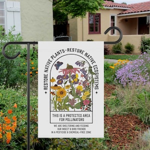 May include: A white garden flag with a colourful illustration of wildflowers and a butterfly. The text reads "Restore Native Plants Restore Native Ecosystems. This is a protected area for pollinators. We are sheltering and feeding our insect and bird friends in a pesticide and chemical-free zone."