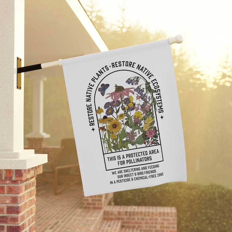 May include: A white flag featuring a colourful illustration of wildflowers within a window frame. The text reads "Restore Native Plants - Restore Native Ecosystems" and "This is a protected area for pollinators. We are sheltering and feeding our insect and bird friends in a pesticide and chemical-free zone."