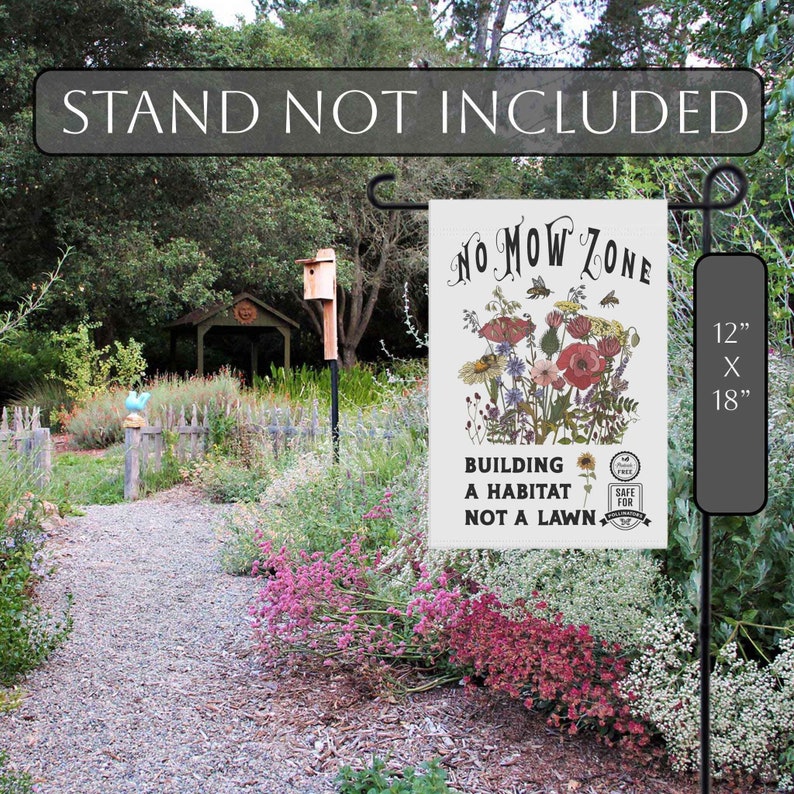 K&ouml;nnte beinhalten: Eine Gartenflagge mit dem Text "NO MOW ZONE" und einem floralen Design. Die Flagge misst 30 cm x 46 cm und tr&auml;gt den Schriftzug "BUILDING A HABITAT NOT A LAWN". Die Flagge wird in einem Garten gezeigt.