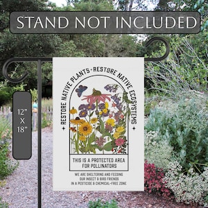 May include: A white garden flag featuring a colourful illustration of wildflowers within a circular frame. The text "RESTORE NATIVE PLANTS+RESTORE NATIVE ECOSYSTEMS" is printed around the frame. The text "THIS IS A PROTECTED AREA FOR POLLINATORS" is printed below the frame. The text "WE ARE SHELTERING AND FEEDING OUR INSECT & BIRD FRIENDS IN A PESTICIDE & CHEMICAL-FREE ZONE" is printed below the text.
