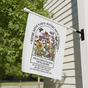 May include: White flag with a black border and text that reads "Restore Native Plants Restore Native Ecosystems". The flag features a colourful illustration of a variety of flowers and a butterfly in a rounded arch shape. The text below the illustration reads "This is a protected area for pollinators. We are sheltering and feeding our insect & bird friends in a pesticide & chemical-free zone."
