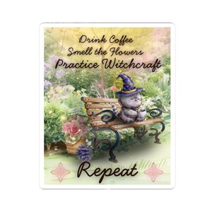 May include: A sticker with a whimsical design. It depicts a gray cat in a witch's hat, enjoying a coffee on a bench. The text says "Drink Coffee, Smell the Flowers, Practice Witchcraft, Repeat." The background is a garden scene.