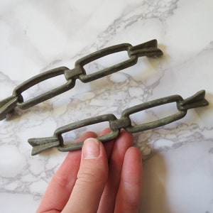 Puede incluir: Dos tiradores de cajón de metal antiguo en forma de eslabón de cadena. Los tiradores son de color bronce oscuro envejecido.