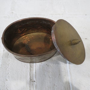 Op de afbeelding: Een ovale messing doos met een deksel. De doos heeft een reli&euml;fmotief en een kleine knop op het deksel.
