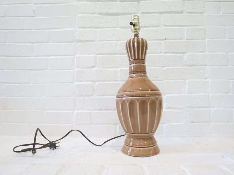 May include: A brown ceramic table lamp with a white stripe design. The lamp has a cord and plug.