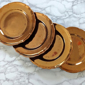 以下が含まれることがあります： 波打つ縁のある金色のチャージャー皿が4枚。皿は重ねられています。