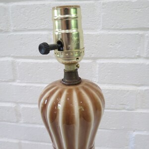 May include: A brown and white ceramic table lamp with a gold metal lampshade holder. The lampshade holder has a switch on the side.