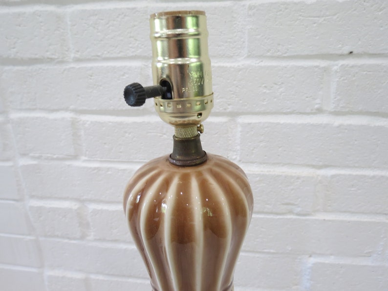 May include: A brown and white ceramic table lamp with a gold metal lampshade holder. The lampshade holder has a switch on the side.