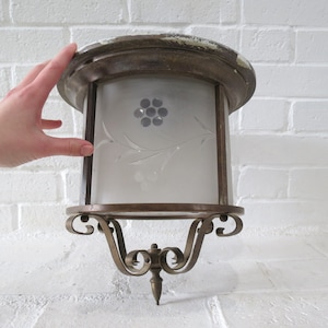Puede incluir: Una lámpara de techo vintage de latón y vidrio con una pantalla de vidrio esmerilado que presenta un diseño floral grabado. La lámpara tiene una base decorativa con volutas.