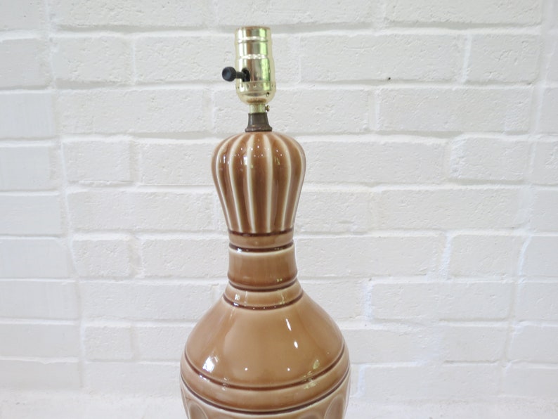 May include: A brown ceramic table lamp with a white stripe design. The lamp has a simple, classic design and would look great in a variety of home decor styles.