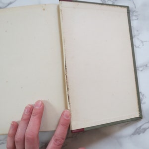 K&ouml;nnte beinhalten: Ein ge&ouml;ffnetes Buch mit gr&uuml;nem Einband und wei&szlig;en Seiten. Das Buch liegt flach auf einer wei&szlig;en Marmorfl&auml;che.
