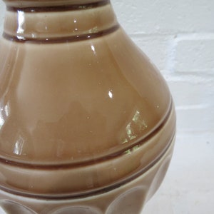 May include: A brown ceramic lamp base with a textured, ribbed design. The base has a glossy finish and a wide, rounded shape.