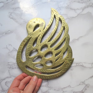 Peut inclure: Un dessous de plat en laiton en forme de cygne avec un motif complexe. Le dessous de plat est en laiton massif et a une finition dorée.