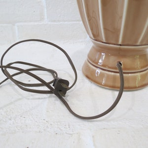 May include: A brown ceramic table lamp with a cord and plug. The lamp has a fluted design and a wide base.