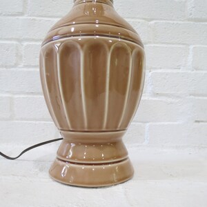 May include: A brown ceramic table lamp with a fluted design. The lamp has a round base and a cord.