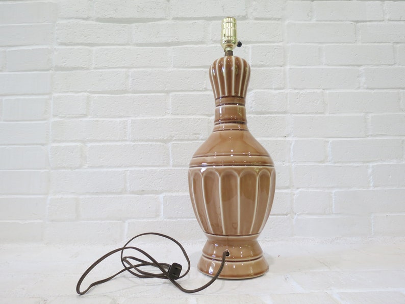 May include: A brown ceramic table lamp with a white ribbed design. The lamp has a gold-colored metal base and a brown cord.