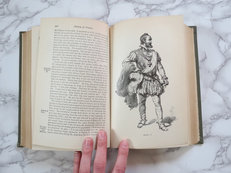 K&ouml;nnte beinhalten: Ein offenes Buch mit einer Schwarzwei&szlig;illustration eines Mannes in historischer Kleidung. Das Buch tr&auml;gt den Titel "Geschichte Frankreichs" und die Seitenzahl ist 320.