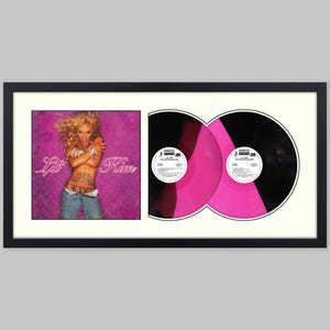 May include: A framed display featuring the Lil' Kim Hard Core album cover art on the left and two vinyl records on the right. The records are black with bright pink centers. The album cover shows Lil' Kim in blue jeans against a purple background.
