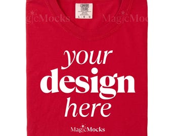 Puede incluir: Una camiseta roja de cuello redondo con el texto blanco your design here impreso en el centro. La prenda tiene una etiqueta de la marca Comfort Colors en el interior del cuello que indica la talla large. El tejido es de color rojo sólido.