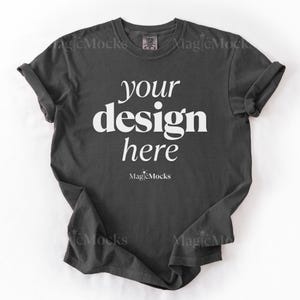 May include: A dark charcoal gray short-sleeve crew neck t-shirt featuring the white text "your design here" printed in the center of the chest. Below the text, the word "MagicMocks" is printed in a smaller white font with a star icon.