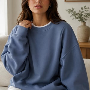 Peut inclure: Un sweat-shirt bleu avec un col ras du cou blanc. Le haut à manches longues est de couleur unie et a une coupe décontractée. Le modèle porte un pantalon blanc.