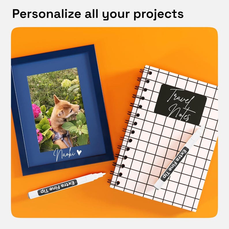 May include: A dark blue picture frame containing a photo of a dog, a spiral-bound notebook with a black and white grid pattern and the text Travel Notes, and two white markers labeled Extra Fine Tip. The text Personalize all your projects is visible.