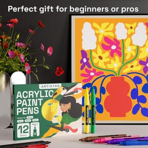 May include: A box of 12 acrylic paint pens with a medium tip, perfect for rocks, glass, wood, and paper. The box is green with the brand name "ARTISTRO" and a colorful illustration. The image also shows a colorful floral painting.