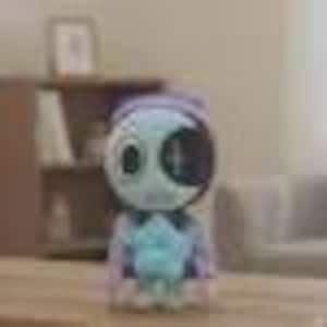 May include: A small, light blue and white figurine of a character with a large, round head and a cross-shaped design on its face. The figurine is wearing a blue and purple outfit and is sitting on a wooden surface.