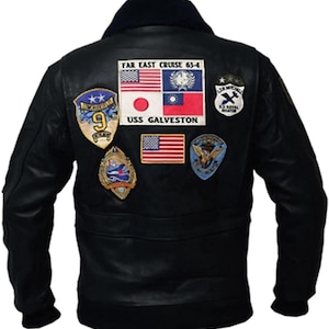 May include: Black leather jacket with a dark blue fur collar. The back of the jacket features multiple patches, including flags and military insignia. The text "FAR EAST CRUISE 63-4" and "USS GALVESTON" are visible on the patches.