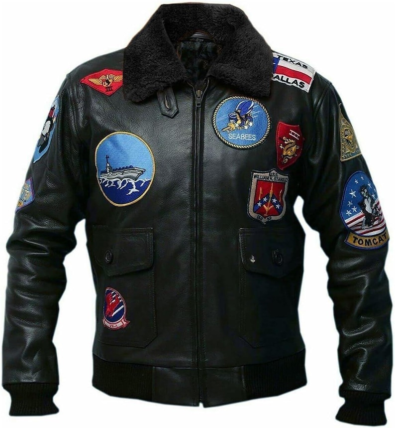 May include: Black leather jacket with multiple embroidered patches, including "Texas Dallas" and "Tomcat." The jacket features a black faux fur collar, two front pockets, and a ribbed hem and cuffs. A classic bomber jacket style.