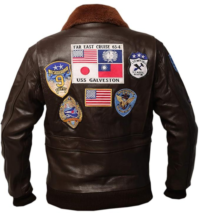 May include: A brown leather bomber jacket with a brown fur collar. The back of the jacket features several embroidered patches, including flags and text that reads "FAR EAST CRUISE 63-4" and "USS GALVESTON". The jacket has a ribbed hem and cuffs.