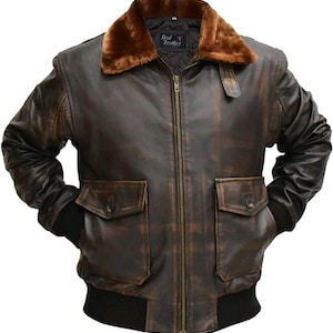 May include: A dark brown leather bomber jacket featuring a plush brown faux fur collar, a central brass-toned zipper, and two large front flap pockets with button closures. The jacket includes black ribbed cuffs and a black ribbed hem at the waist.