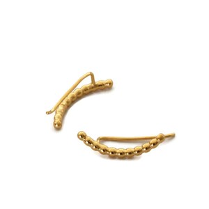 May include: A pair of gold ear cuffs with a beaded design. The cuffs are curved and have a simple, minimalist style.
