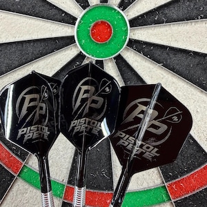 May include: Three black darts with silver accents and the text "PISTOL PETE" are positioned in front of a dartboard. The dartboard features a green and red bullseye, with black and white alternating sections.