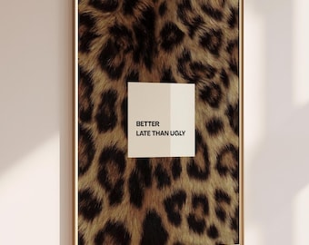 May include: A rectangular wall art print in a thin gold frame featuring a brown and black leopard print pattern. Centered on the print is a white square containing the black text "BETTER LATE THAN UGLY" in a clean, sans-serif typeface.