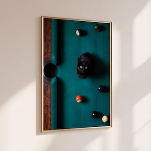 May include: A framed vertical wall art print featuring a top-down view of a dark green pool table surface. A black cat sits in the centre surrounded by scattered colourful billiard balls. The table has a dark wood grain side rail and a black pocket.
